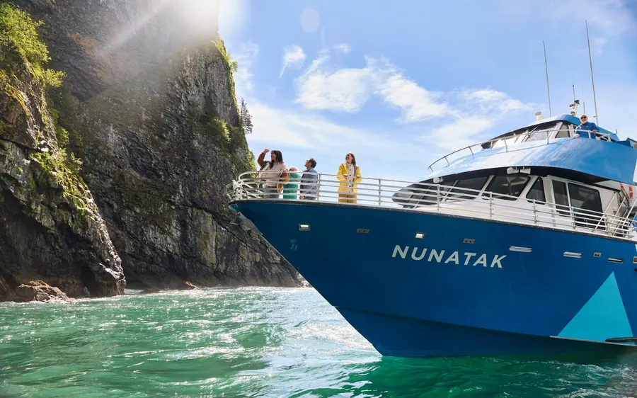 A cruise boat beside the blue face of a tidewater glacier in Kenai Fjords
