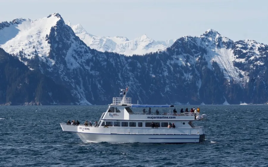 A tour boat in front of snow-covered mountains in Resurrection Bay, Alaska